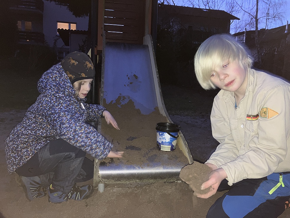 Zwei Kinder durchsuchen den Sand