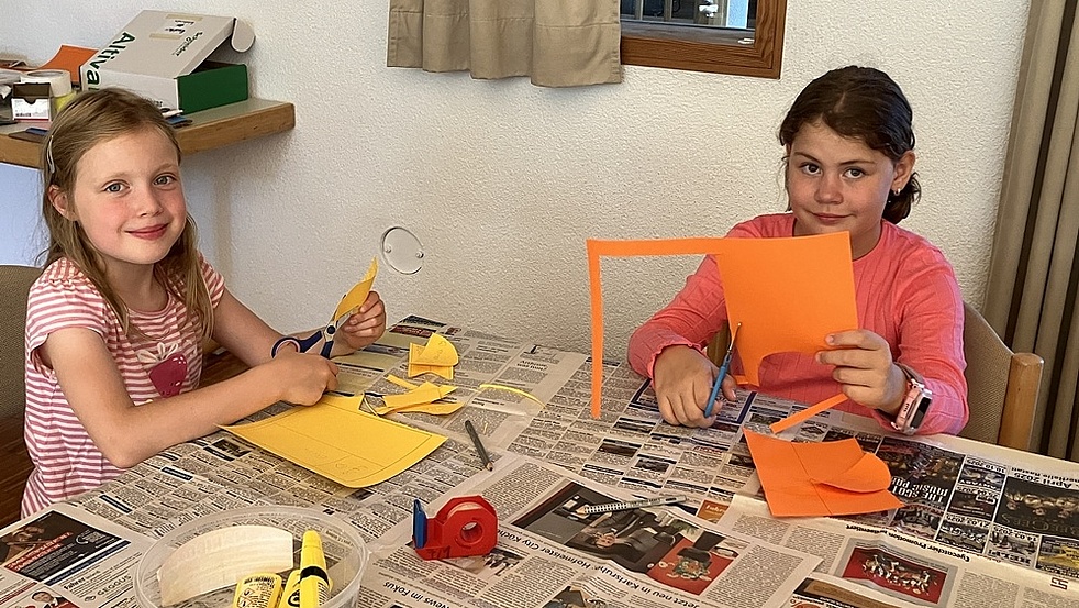 Papier ausschneiden Zwei Kinder schneiden Pappe aus, um daraus die Rakete zu bauen