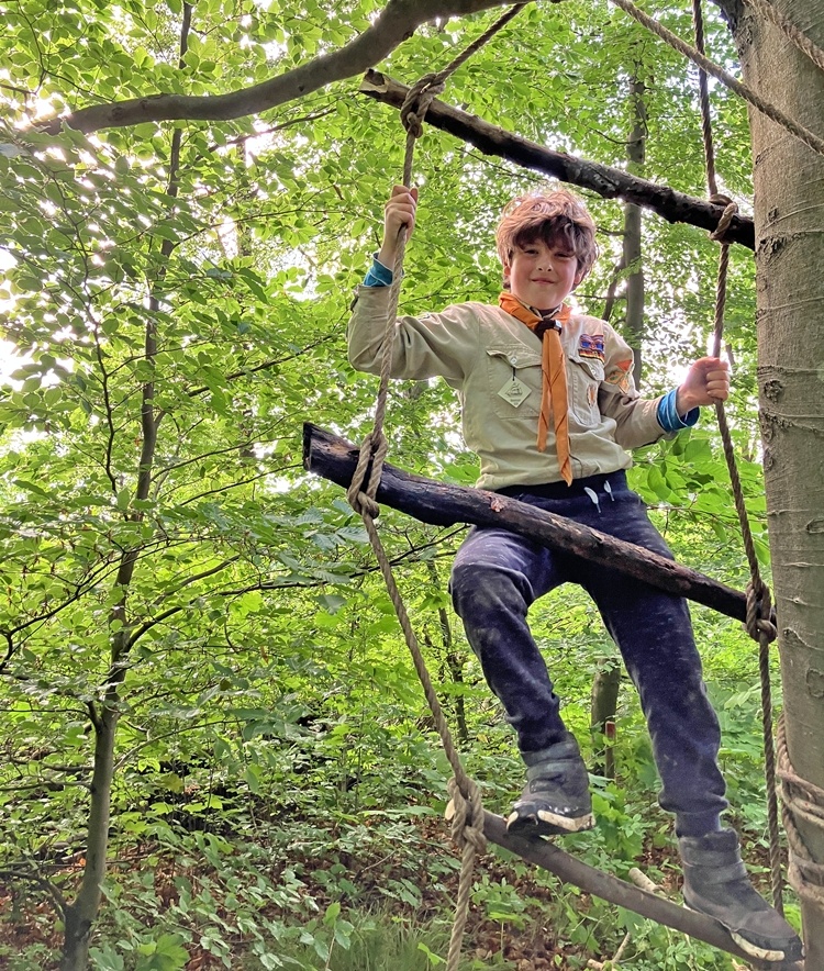 Strickleiter Ein Pfadfinder klettert auf einer selbstgebauten Strickleiter