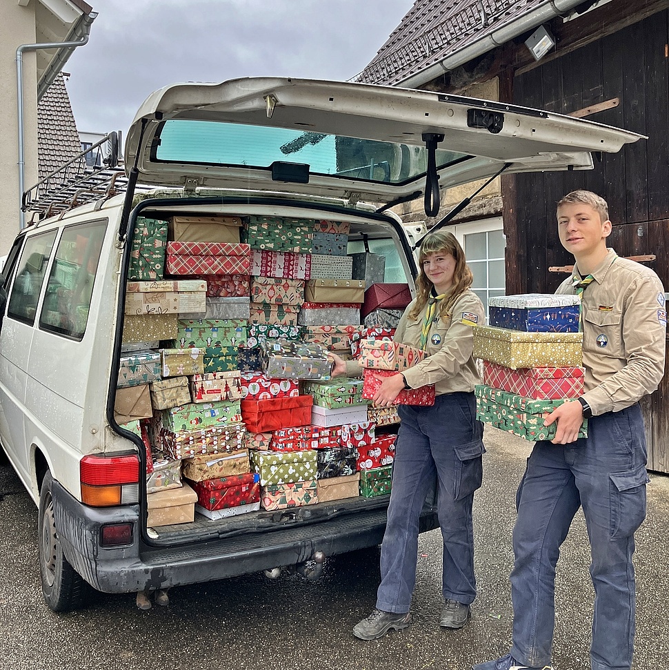 Pfadfinder packen Kartons in Fahrzeug Zwei Pfadfinder packen gepackte Geschenkpäcken in ein Fahrzeug